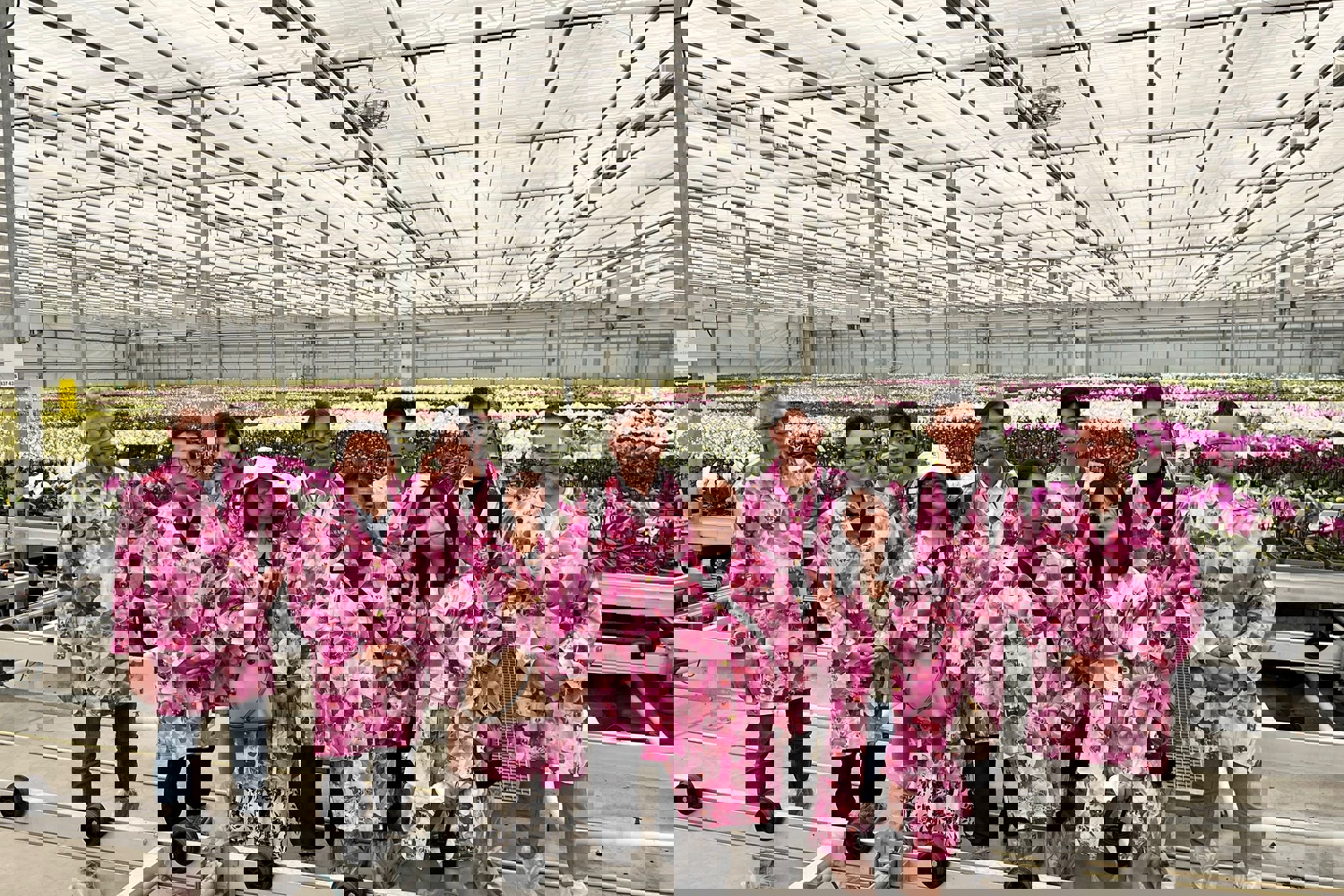 Group of people in floral coats in a greenhouse with orchids