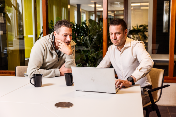 Twee medewerkers werken samen met SDF software aan data en processen op een laptop